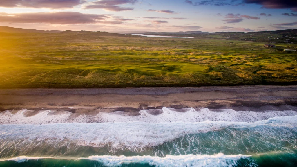 Stunning coastal view in Ireland, featuring vibrant green landscapes meeting the waves of the Atlantic Ocean.
