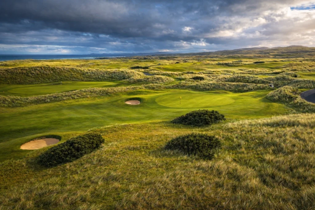 Scenic view of a lush Irish golf course with sand traps under a cloudy sky. Ideal for golf enthusiasts.