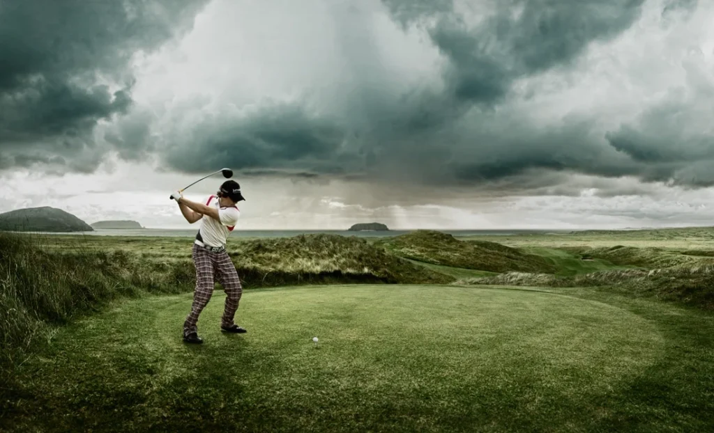 Golfer preparing to swing in a dramatic, cloudy landscape on a golf course in Ireland. Perfect for golf enthusiasts!