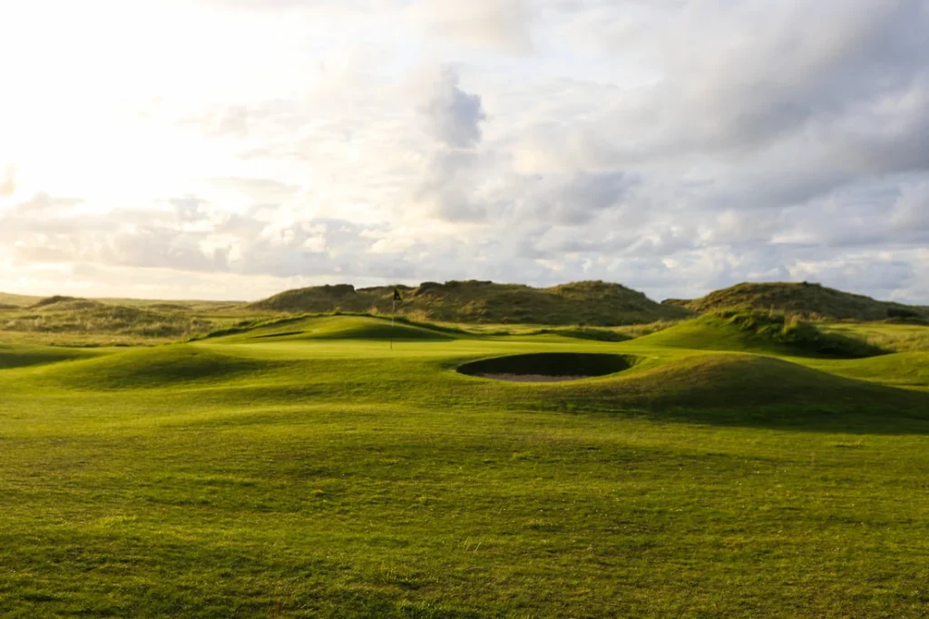 Scenic golf course landscape featuring lush greens, sand bunkers, and a dramatic sky. Perfect for golf enthusiasts.