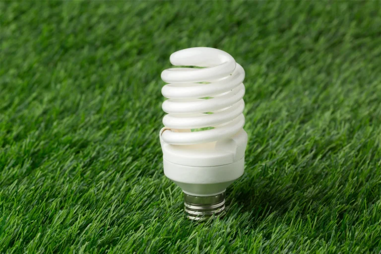 Energy-efficient spiral light bulb on green grass backdrop, perfect for eco-friendly lighting solutions.