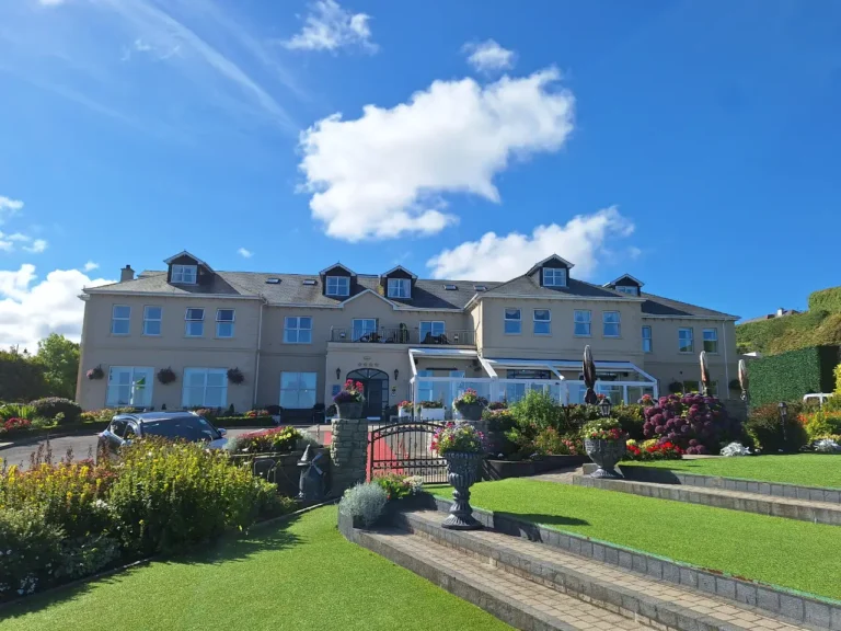 Charming hotel surrounded by vibrant gardens and blue skies, perfect for a relaxing Irish getaway.