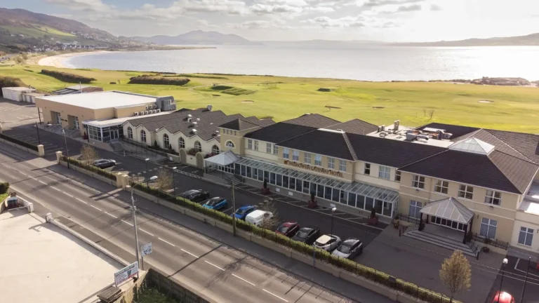 Aerial view of Inisowen Gateway Hotel near scenic coastline and green fields, perfect for relaxing stays.